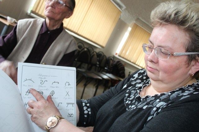 Larisa Pavlovna Avdeeva showing old signatures used by Sami families in official documents before literacy became widespread.